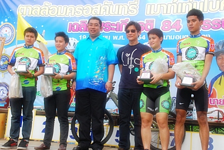 Former Minister for Sports and Tourism, Sonthaya Khunplome, center, presents trophies to one of the winning teams.